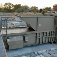 OLYMPUS DIGITAL CAMERA A Stationary Compactor with a beige finish, surrounded by concrete debris and construction materials.