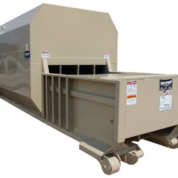 A large industrial compactor with wheels and several warning labels, designed for waste management and storage.