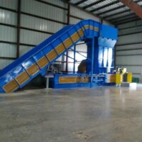 A large blue industrial machine with a conveyor belt inside a warehouse.