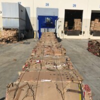 Stacks of compressed cardboard bales lined up outside a warehouse loading dock.