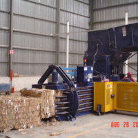 Industrial baler compressing cardboard in a warehouse setting on August 26, 2006.